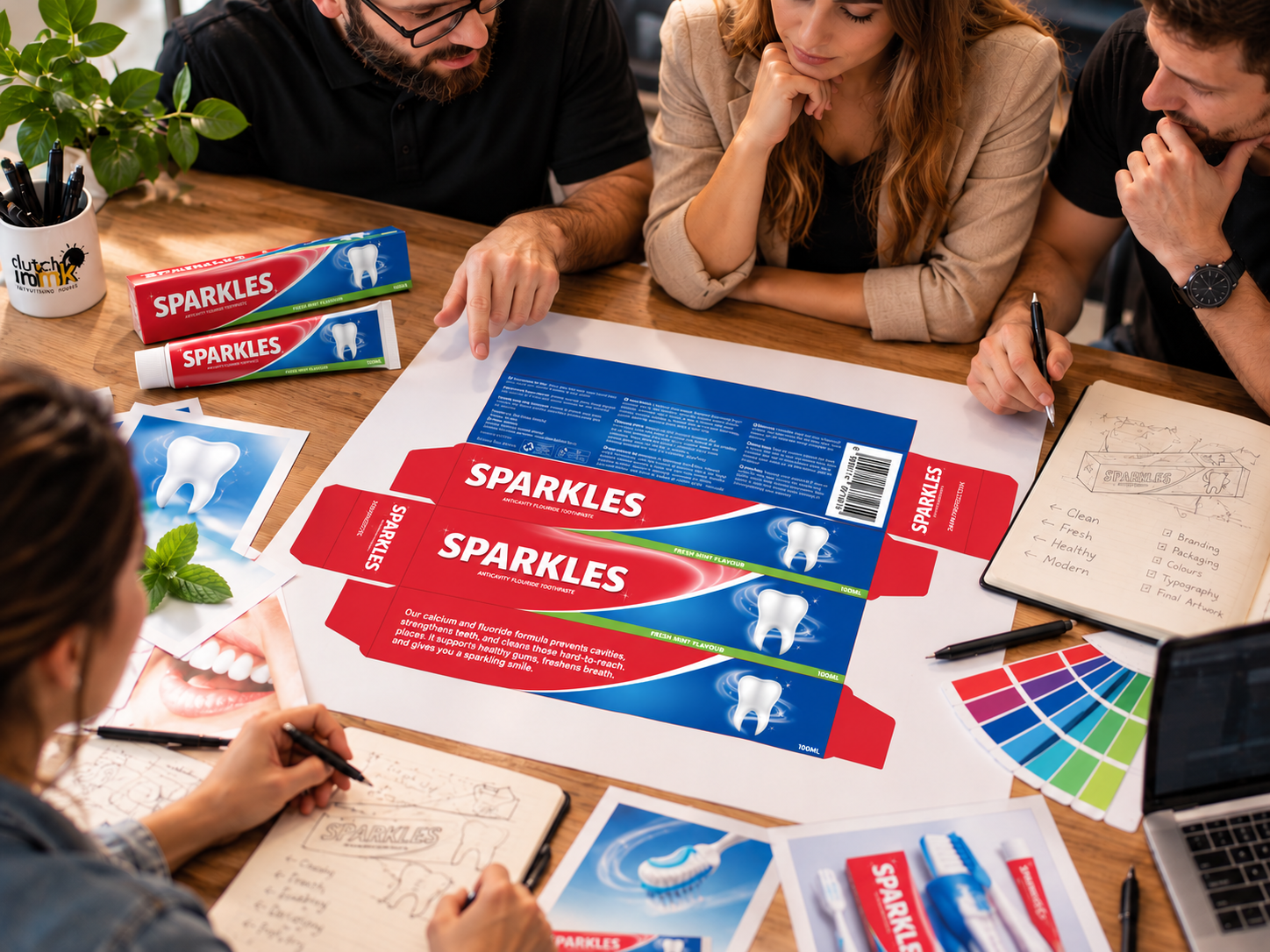 Design team reviewing the SPARKLES toothpaste carton artwork layout, colour swatches and sketches at a table